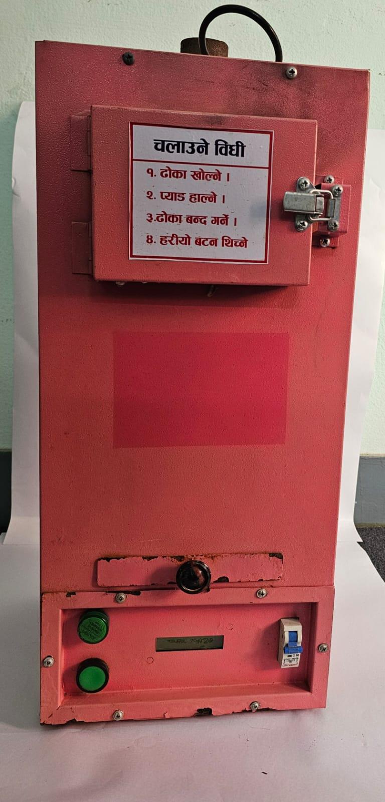 Front view of a pink sanitary pad incinerator machine with top loading door, operating instructions label, power buttons, and safety switch.