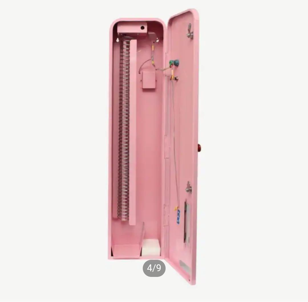 Interior view of an open pink slim vending machine showing the vertical product dispensing spring mechanism and wiring setup.